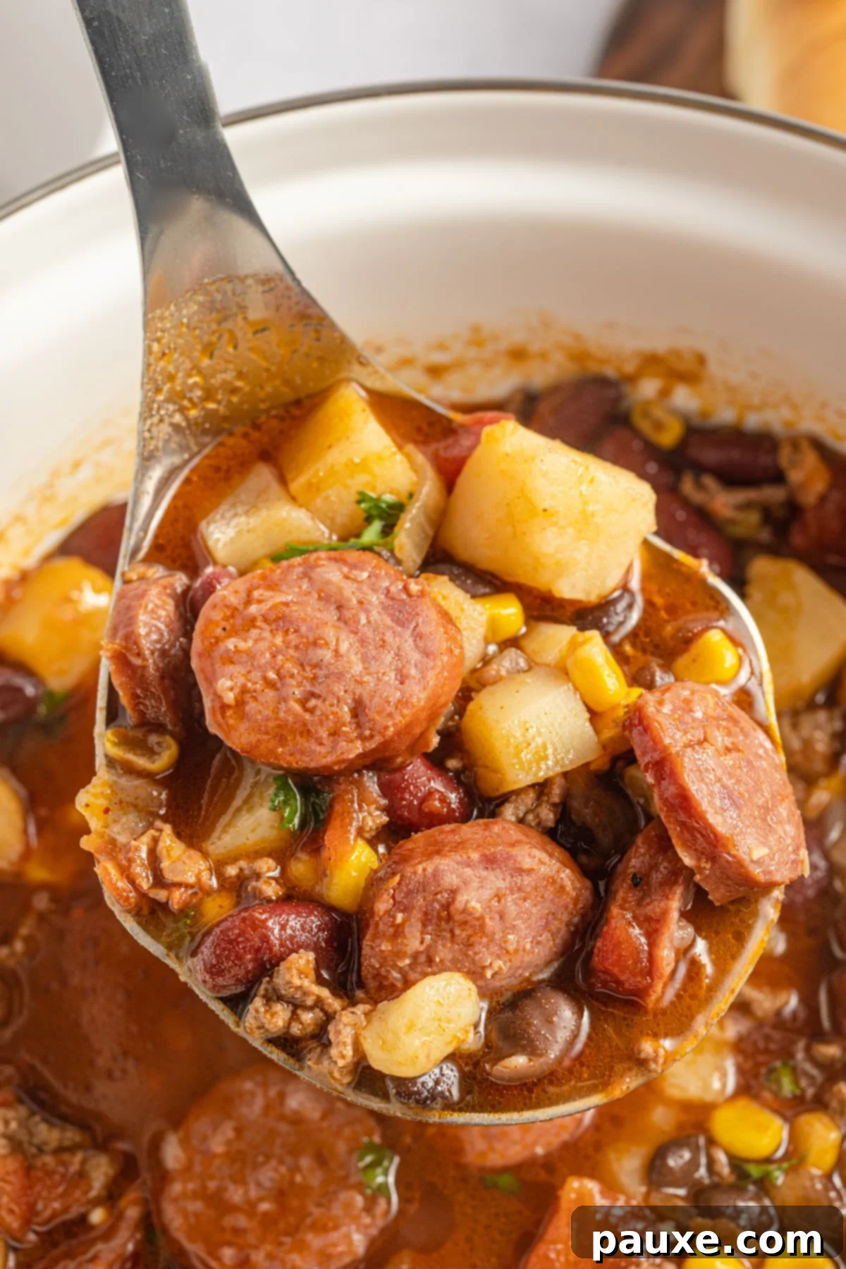 Rancher's Hearty Stew 10 A ladle scooping a hearty portion of Texas Cowboy Stew from a large, rustic pot, emphasizing its thick and wholesome consistency.