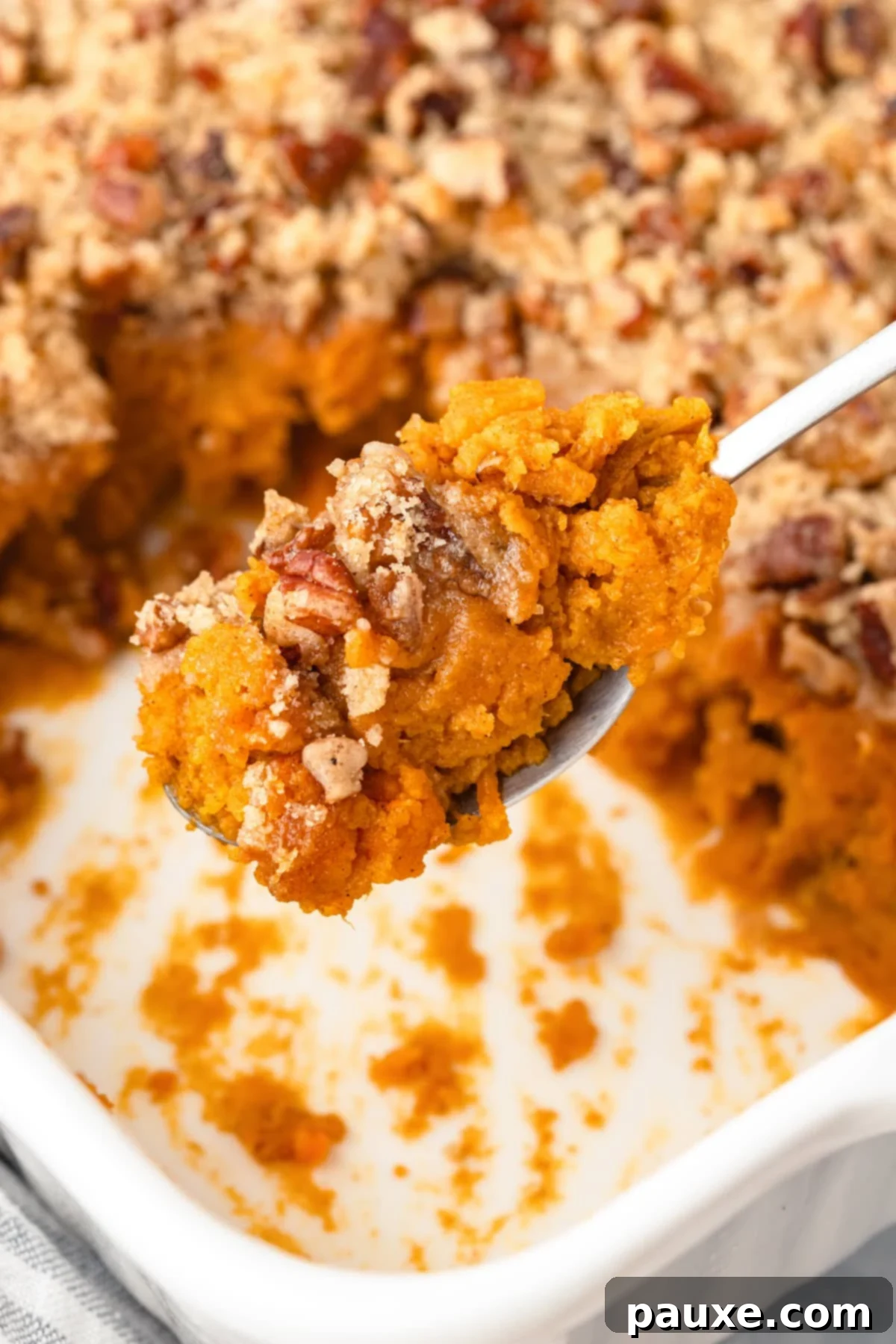 Pecan Streusel Sweet Potato Bake 2 A spoon taking a portion of sweet potato casserole with pecans.