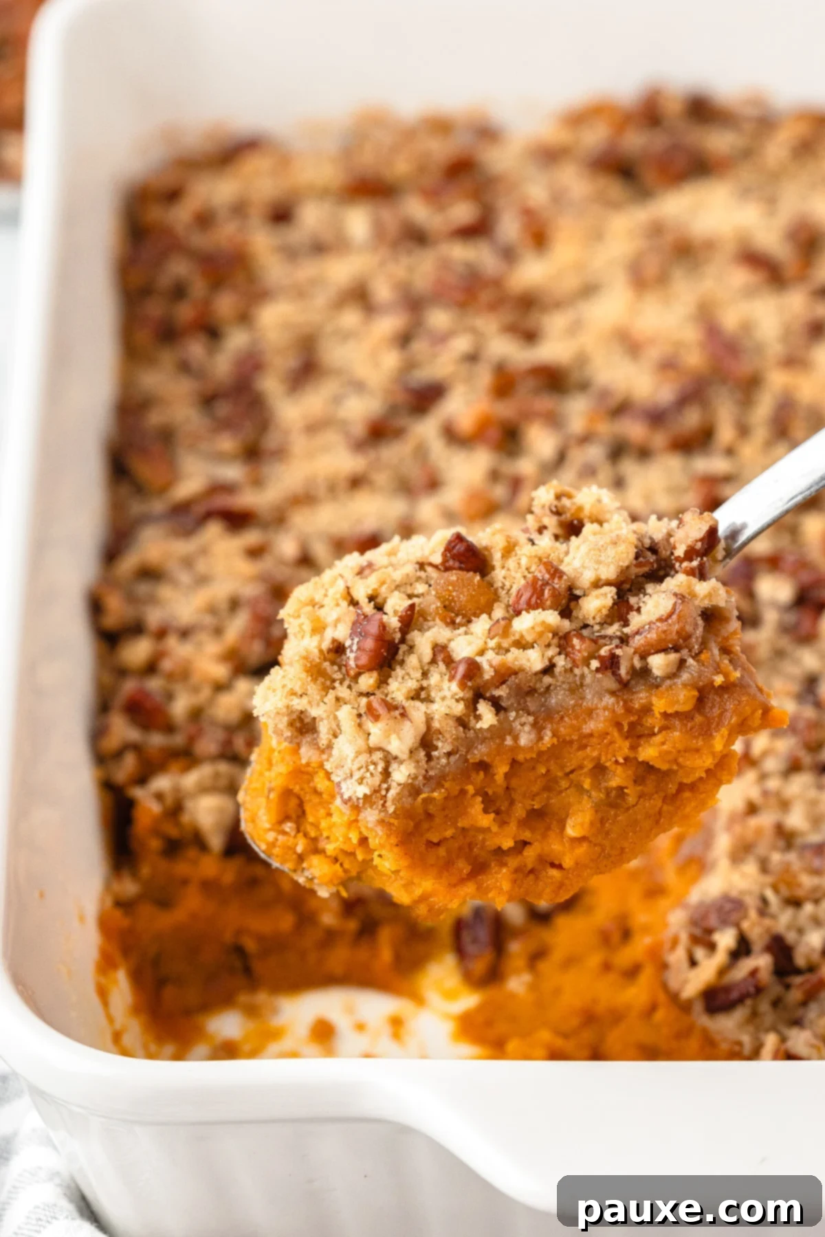 Pecan Streusel Sweet Potato Bake 14 Scooping sweet potato casserole from a baking dish.