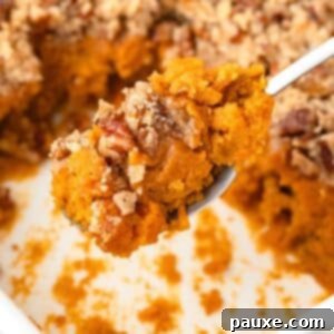 Pecan Streusel Sweet Potato Bake 15 A spoon scooping a portion of sweet potato casserole from a baking dish.