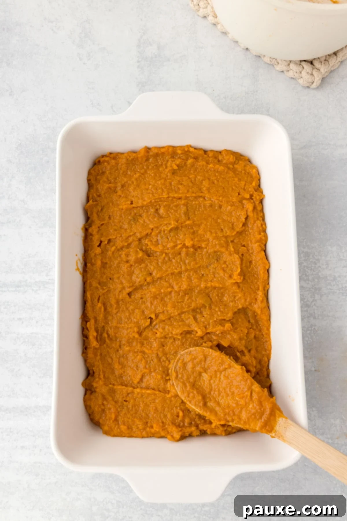 Pecan Streusel Sweet Potato Bake 7 Spreading sweet potato casserole into a baking dish.