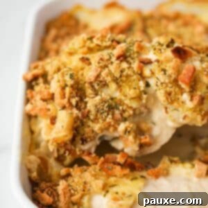Alpine Chicken Comfort Bake 15 Lifting a piece of chicken and stuffing from a baking dish, showcasing the creamy filling and crispy topping.