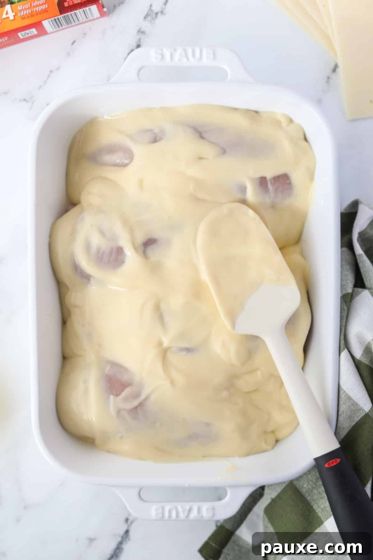 Alpine Chicken Comfort Bake 7 Spreading the creamy soup and sour cream mixture evenly over the chicken breasts in the baking dish.