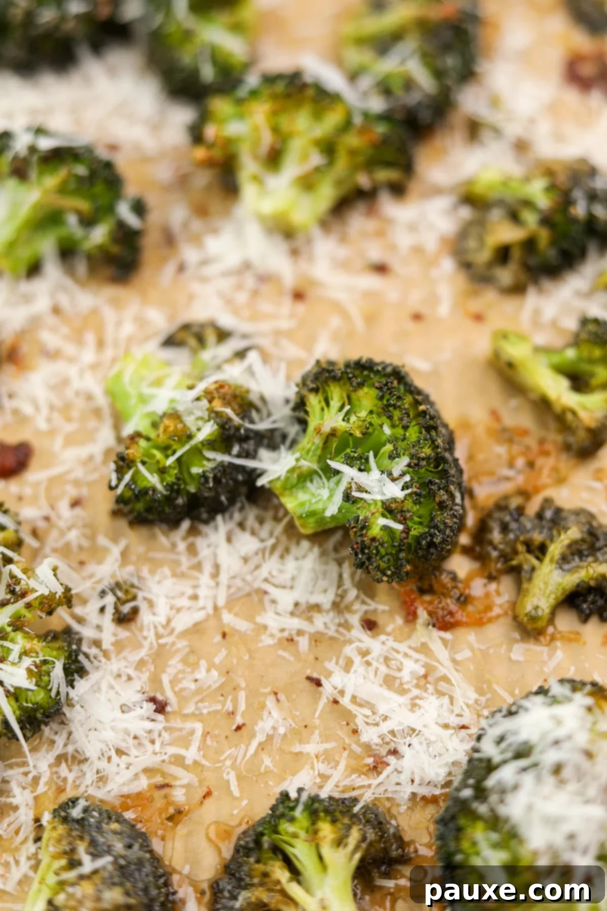 Zesty Ranch Roasted Broccoli 13 Close-up of vibrant roasted broccoli florets on a baking sheet, delicately topped with melted parmesan cheese and hints of ranch seasoning.