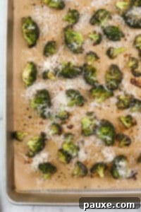 Zesty Ranch Roasted Broccoli 19 Roasted broccoli on a baking sheet topped with parmesan cheese.