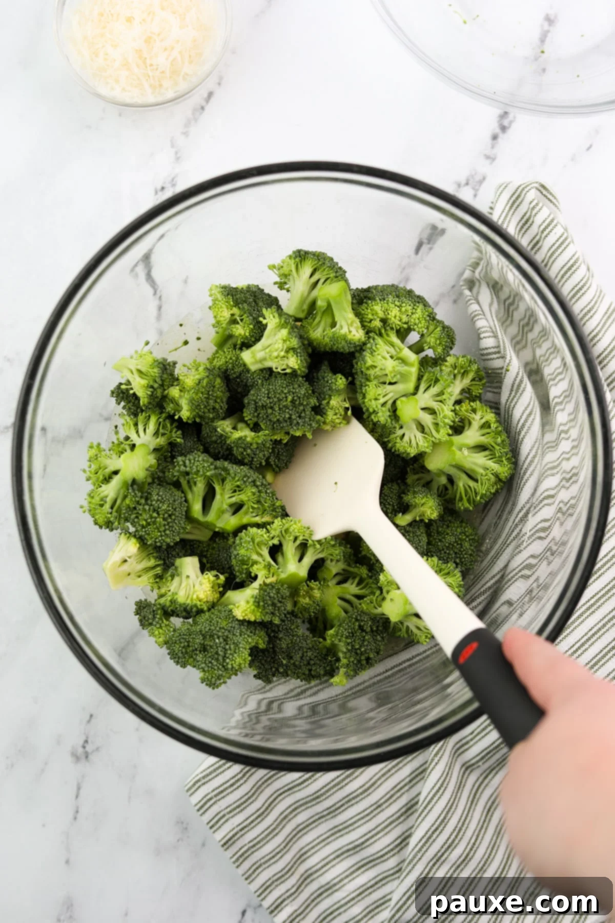Zesty Ranch Roasted Broccoli 7 Fresh broccoli florets being stirred into the seasoned olive oil mixture in a large bowl, ensuring each piece is thoroughly coated.