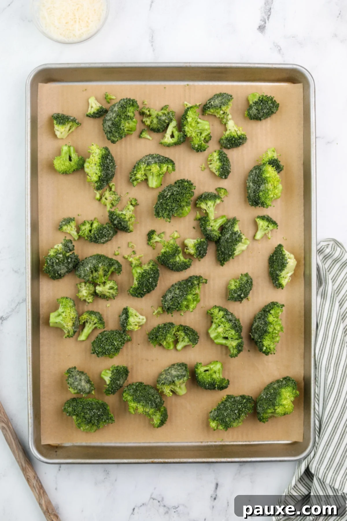 Zesty Ranch Roasted Broccoli 8 Seasoned broccoli florets neatly spread out in a single layer on a parchment-lined baking dish, ready for roasting.