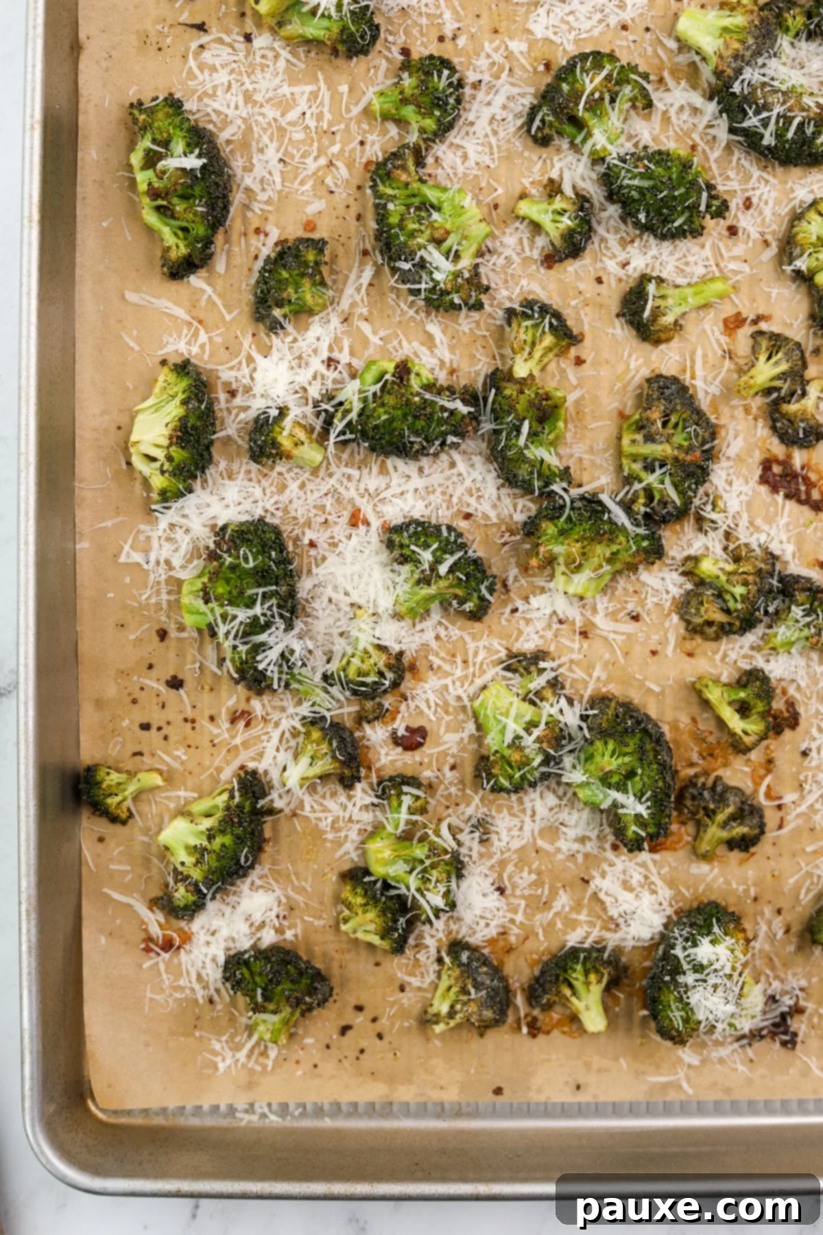Zesty Ranch Roasted Broccoli 10 Golden-brown roasted broccoli on a baking sheet, generously topped with shredded parmesan cheese, creating a delicious finish.