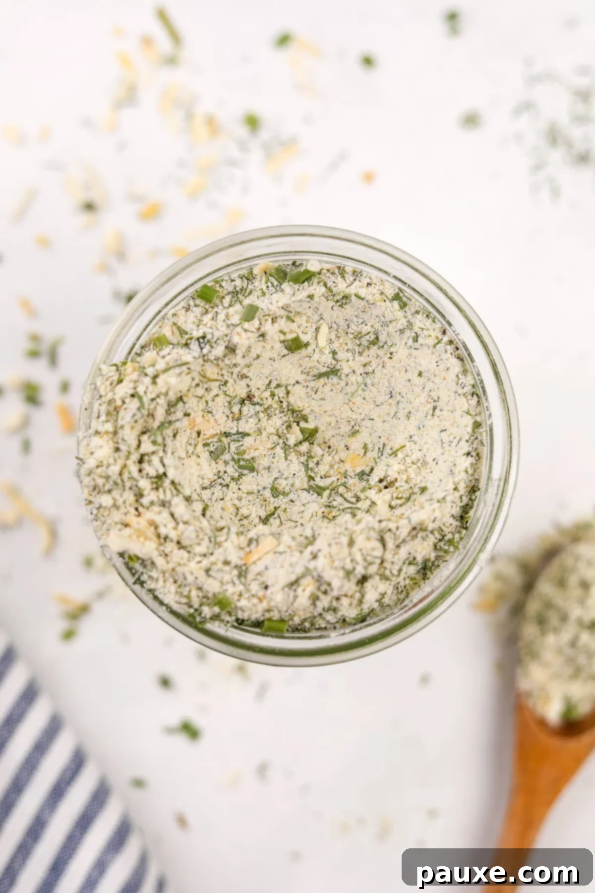 An inviting overhead shot of a glass jar filled with homemade ranch seasoning, showing its texture and fresh ingredients.