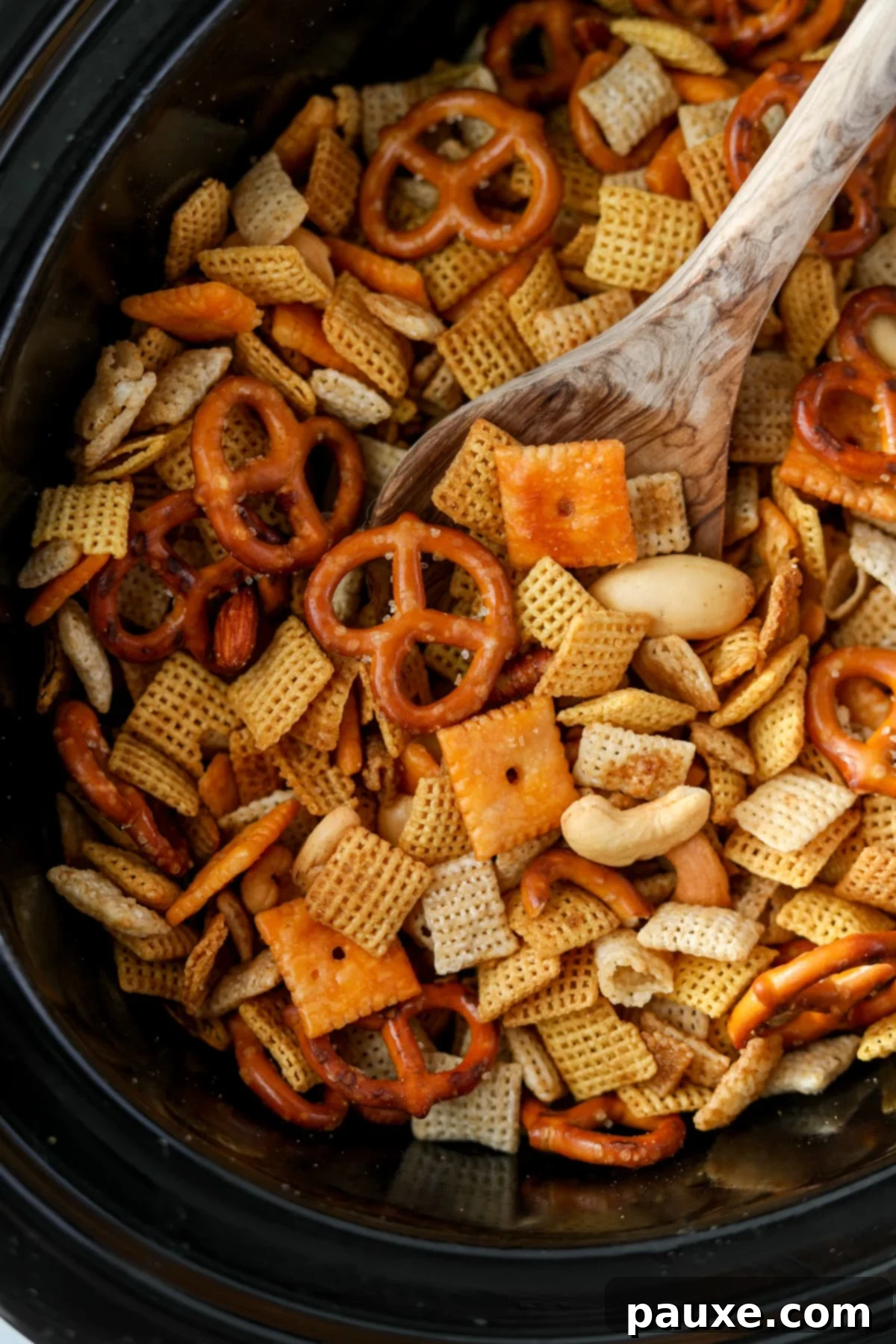 Effortless Slow Cooker Party Mix 12 Someone using a wooden spoon to scoop crispy Chex Mix from a Crock Pot, ready to serve.