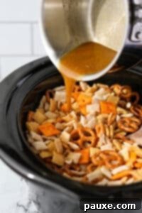 Effortless Slow Cooker Party Mix 17 Pouring melted butter into a slow cooker filled with Chex Mix ingredients.