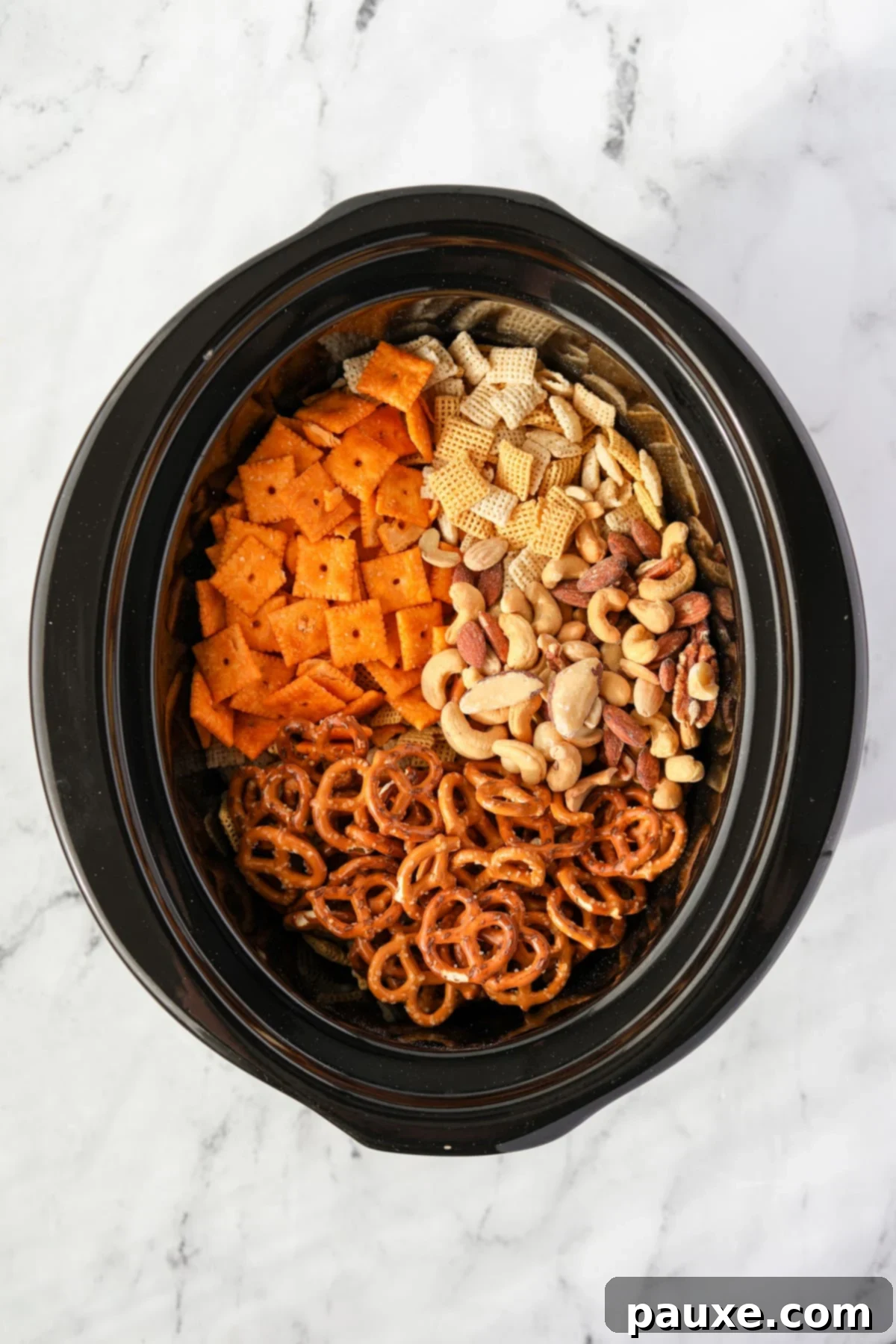 Effortless Slow Cooker Party Mix 4 A slow cooker with chex cereal, crackers, pretzels, and mixed nuts inside, before seasoning.