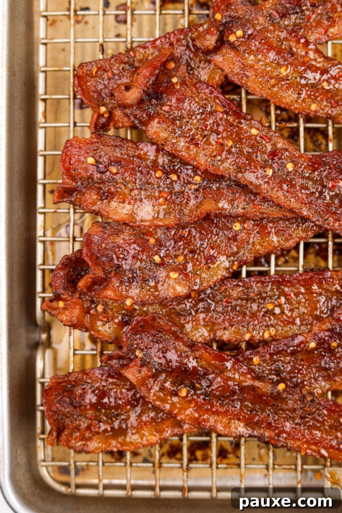 Decadent Glazed Bacon 11 A stack of golden-brown, candied bacon slices resting on a wire baking rack, showcasing the crispy texture and sweet glaze.
