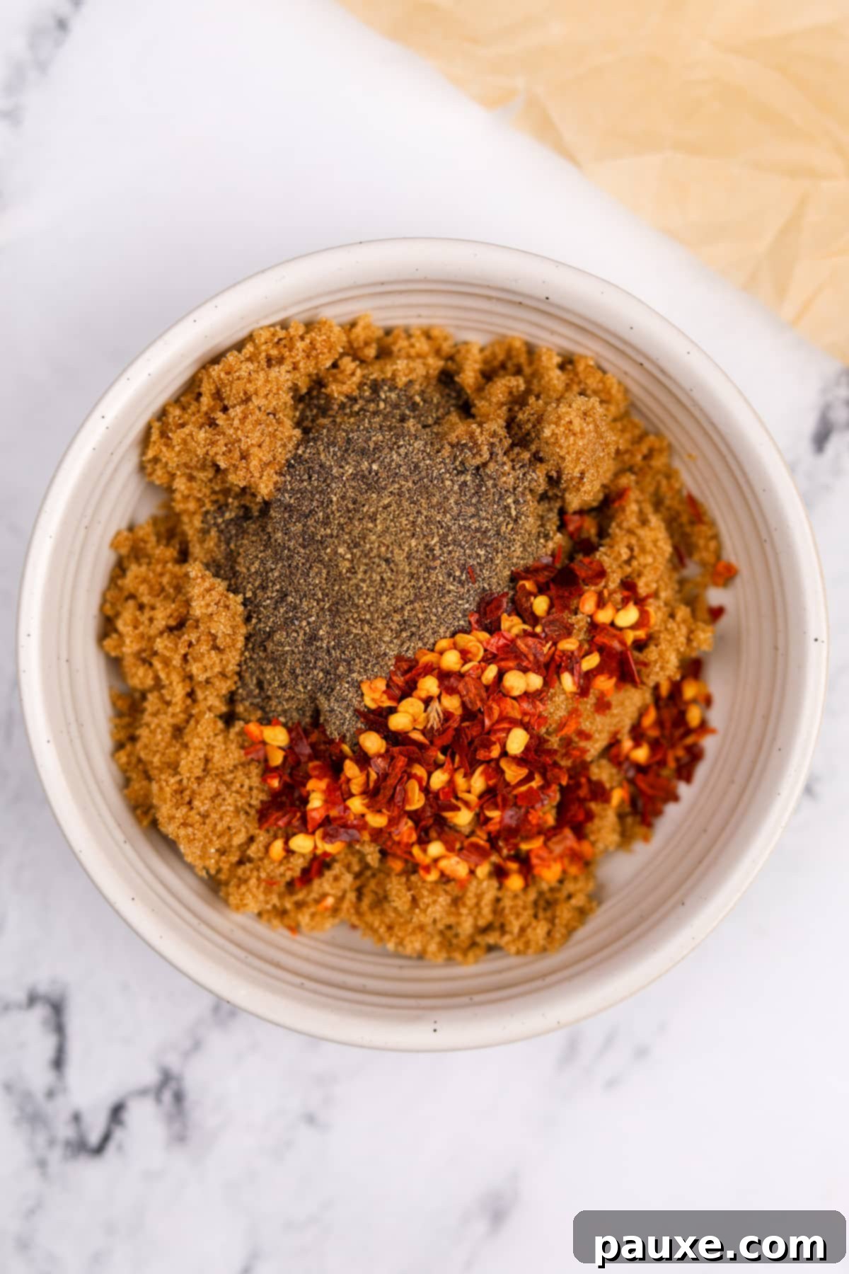 Decadent Glazed Bacon 4 A small bowl holding a mixture of brown sugar, crushed red pepper flakes, and black pepper, ready to be stirred.