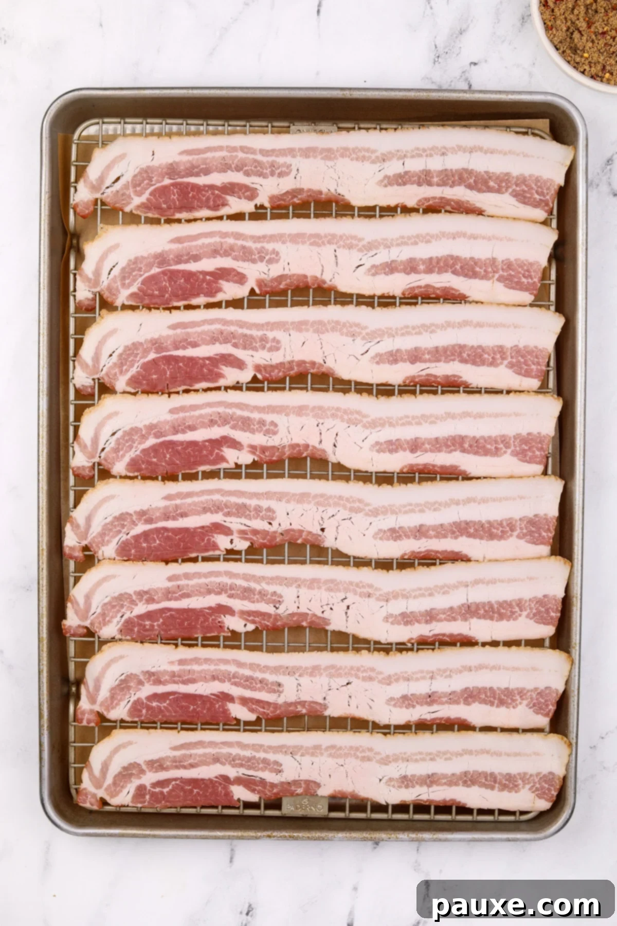 Decadent Glazed Bacon 6 A baking sheet with a wire rack filled with neatly arranged bacon slices, spaced apart.