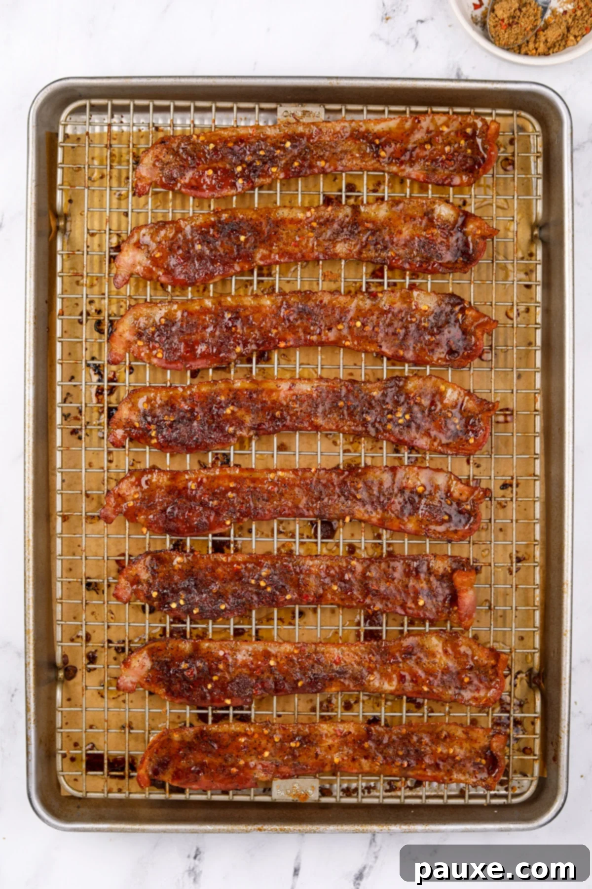 Decadent Glazed Bacon 9 Cooked crispy bacon on a baking sheet, coated with a glistening brown sugar glaze, fresh out of the oven.