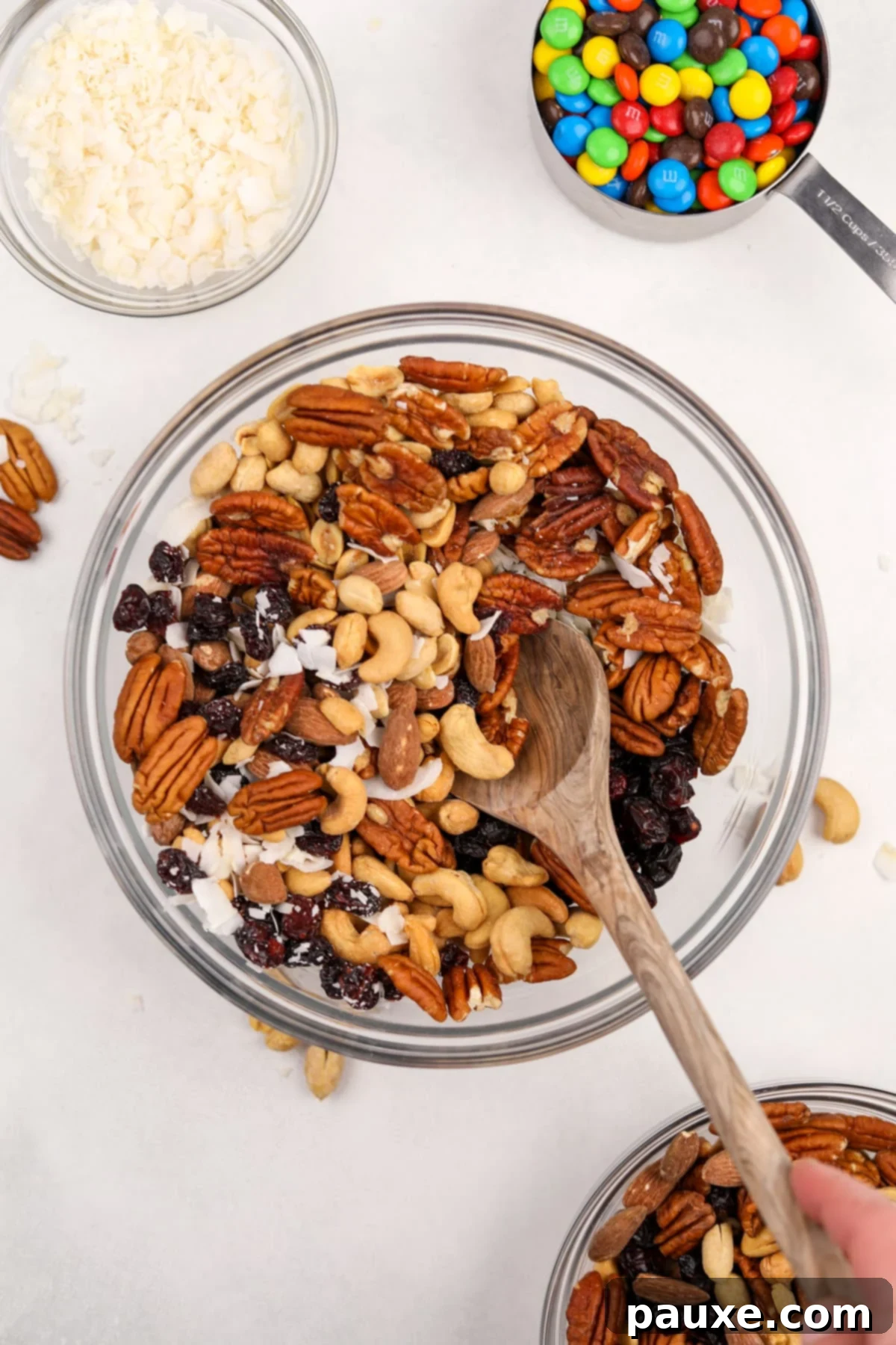 Trailblazer's Blend 5 A large bowl filled with mixed nuts, dried fruit, and coconut, partially stirred.