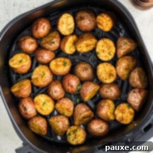 An air fryer basket filled with baby potato halves, golden and ready to be served.