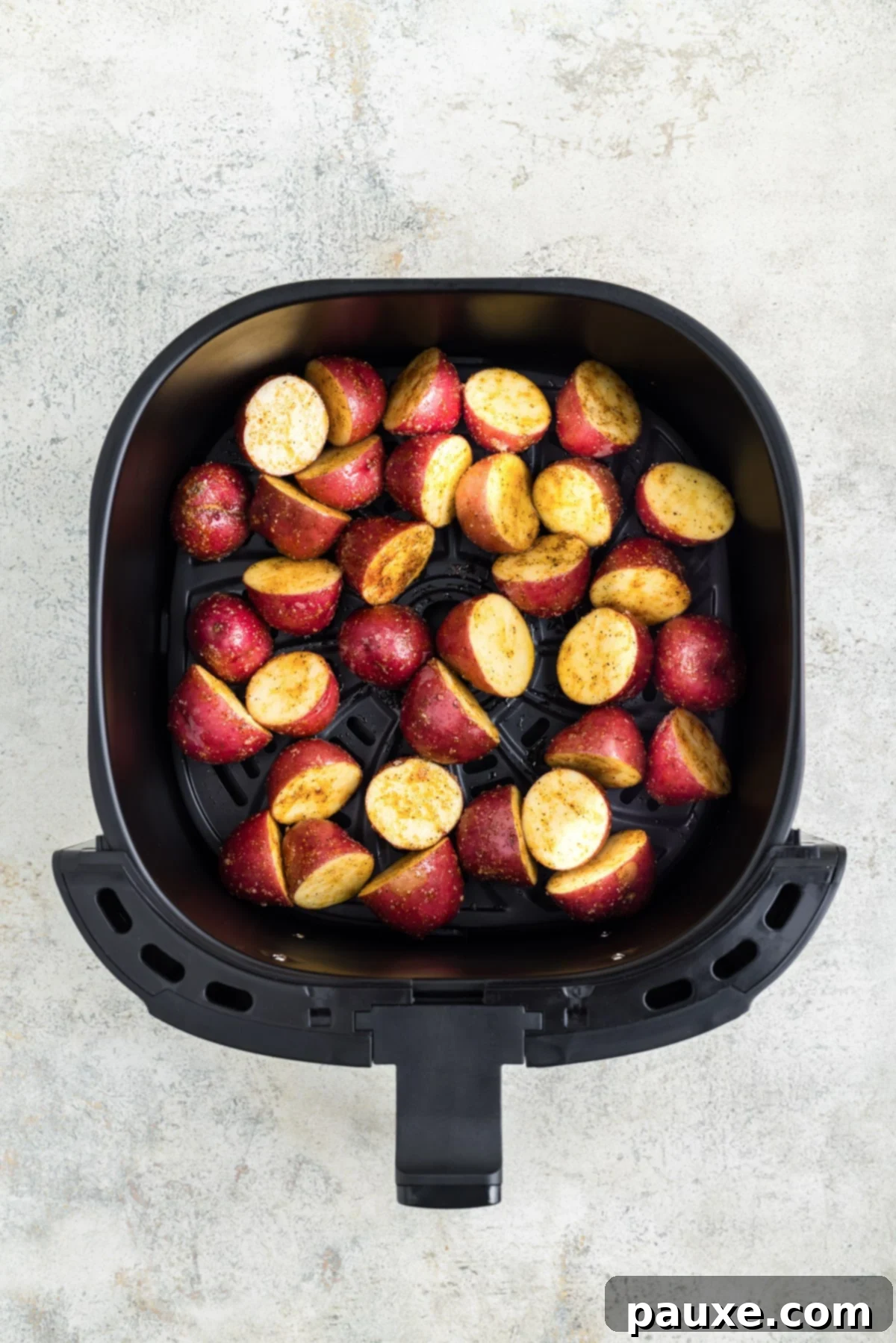 An air fryer basket properly filled with a single layer of seasoned baby potatoes.