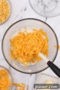 Gluten-Free Cheesy Hash Brown Casserole 22 A large bowl with shredded cheddar cheese inside.