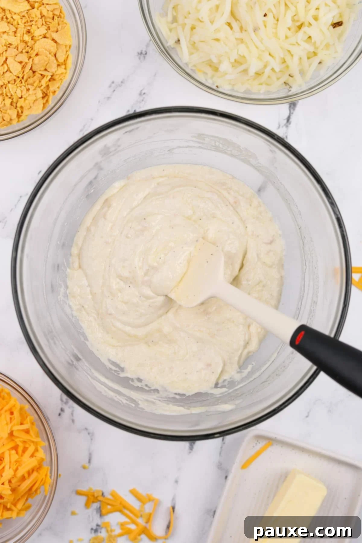 Gluten-Free Cheesy Hash Brown Casserole 5 A large bowl filled with a perfectly smooth, creamy, and savory sauce, expertly blended from sour cream, gluten-free condensed soup, and melted butter, forming the luscious base for the hash brown casserole.