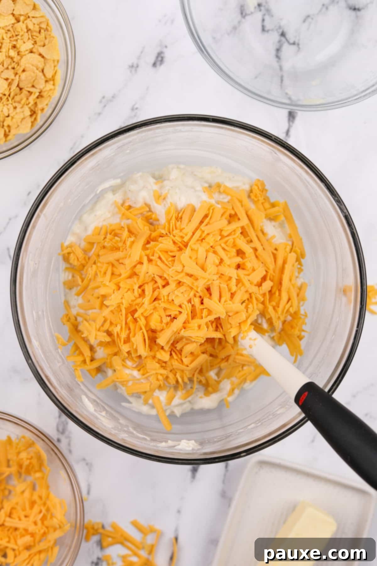 Gluten-Free Cheesy Hash Brown Casserole 7 A generous pile of freshly shredded sharp cheddar cheese in a large mixing bowl, ready to be folded into the creamy potato mixture for the ultimate cheesy funeral potatoes.