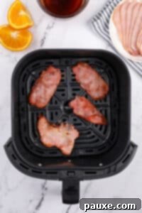 Easy Air Fryer Canadian Bacon 10 An air fryer basket containing four slices of cooked back bacon, perfectly browned and crispy.