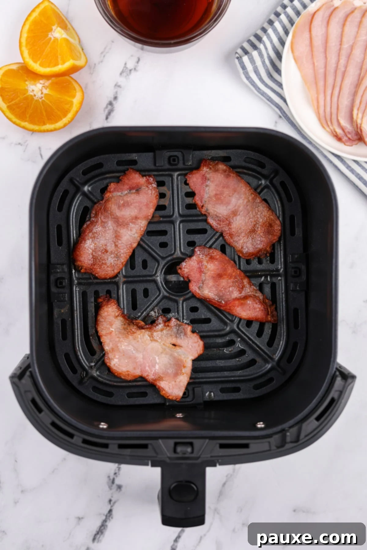 Easy Air Fryer Canadian Bacon 5 An air fryer basket showcasing four perfectly cooked slices of back bacon with crispy edges.