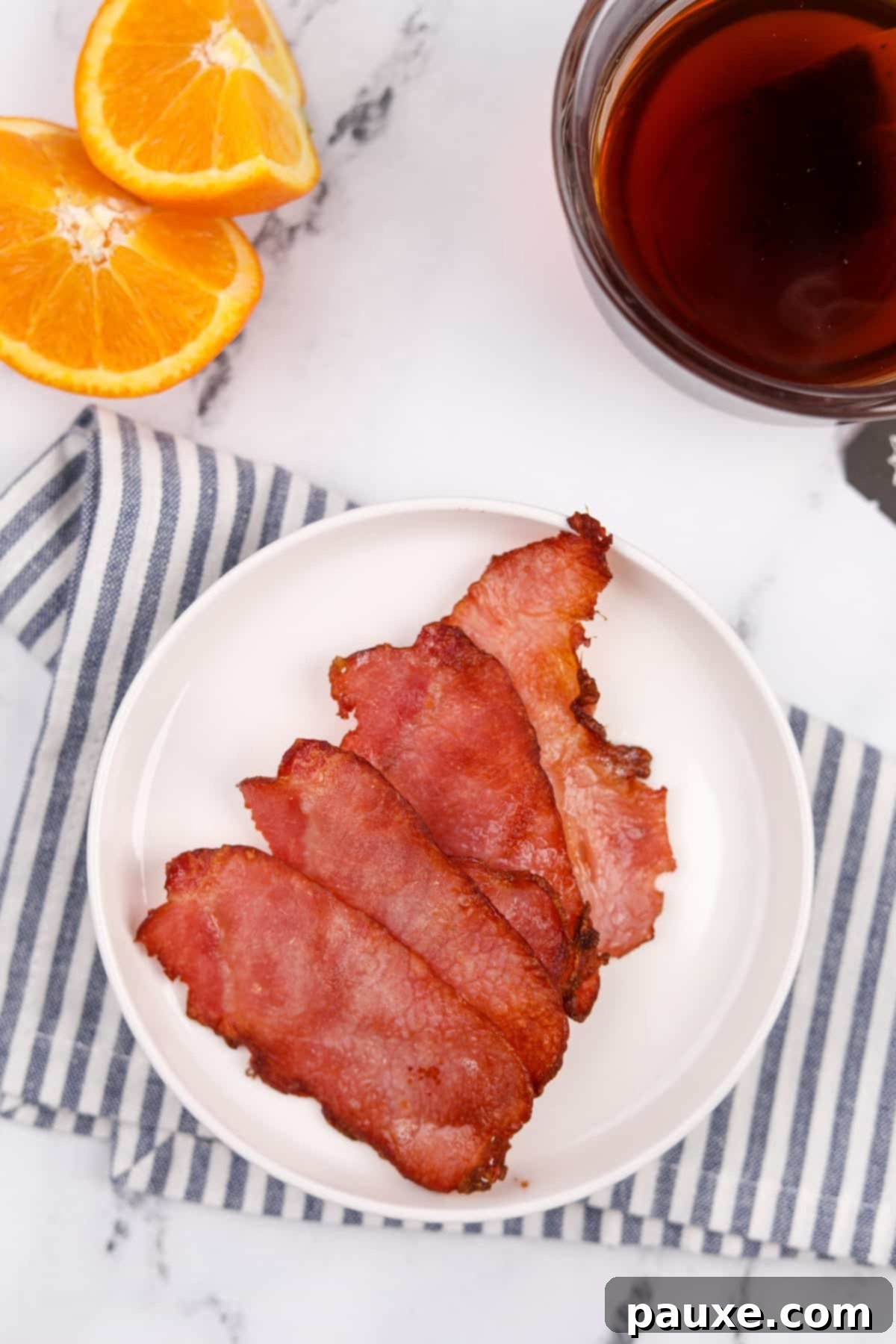 Easy Air Fryer Canadian Bacon 7 A pristine white plate holding four beautifully cooked slices of back bacon.