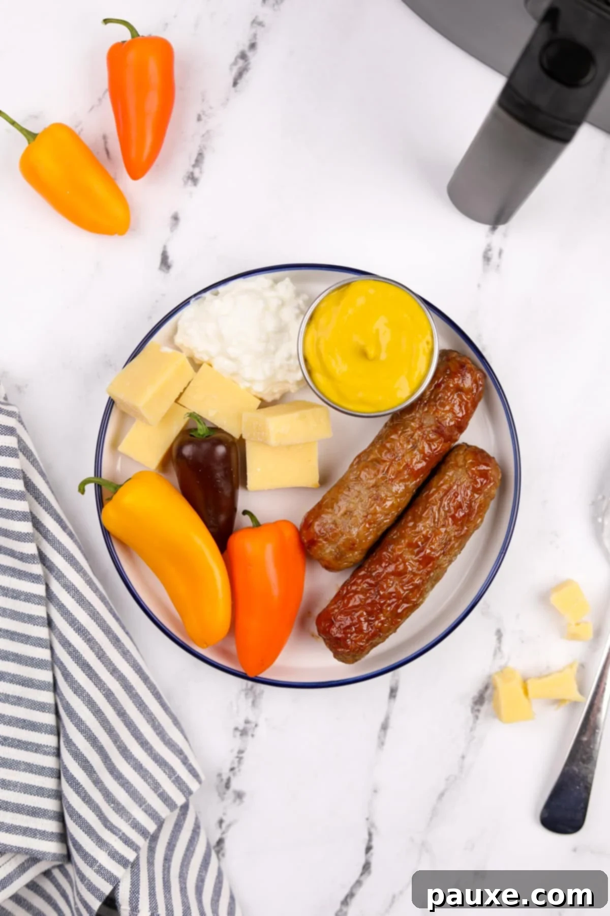 A vibrant plate featuring perfectly air-fried chicken sausages, accompanied by an assortment of fresh vegetables, a dollop of creamy cottage cheese, and a side of tangy mustard.