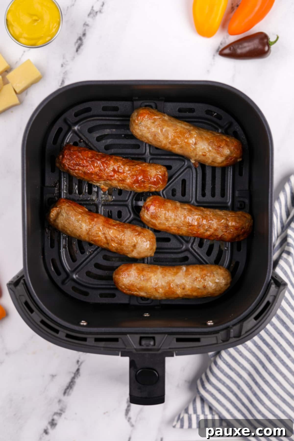 A close-up view of an air fryer basket filled with beautifully cooked chicken sausages, boasting a golden-brown and crispy exterior.