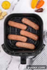 An air fryer basket with chicken sausages in a single layer.