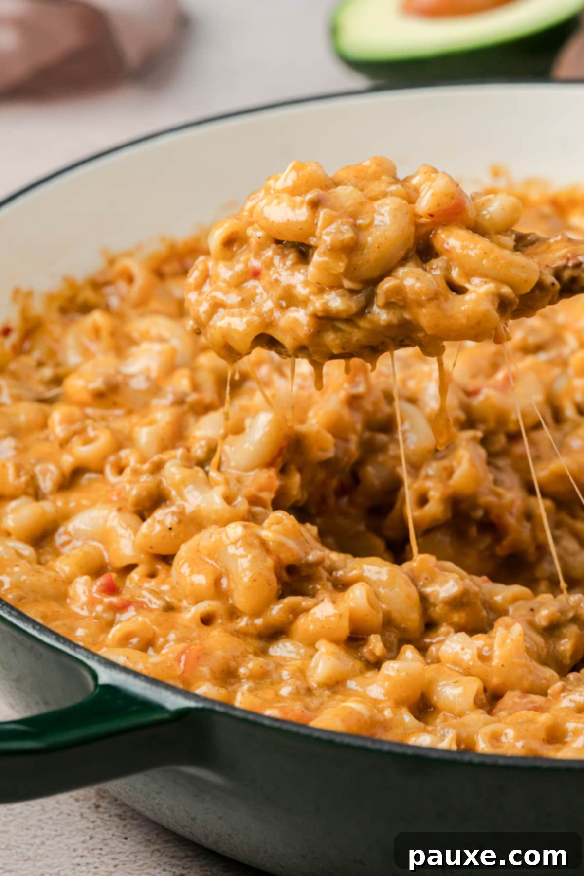 Taco Mac 'n' Cheese Explosion 2 Close-up of a spoonful of Taco Mac and Cheese being lifted from a skillet, showcasing the creamy texture and delicious flavors.