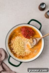 Taco Mac 'n' Cheese Explosion 11 Adding macaroni, broth, milk, and salsa to a skillet.