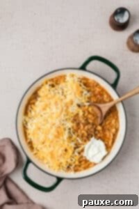 Taco Mac 'n' Cheese Explosion 12 Adding cheese and cream cheese to a skillet with cooked macaroni.