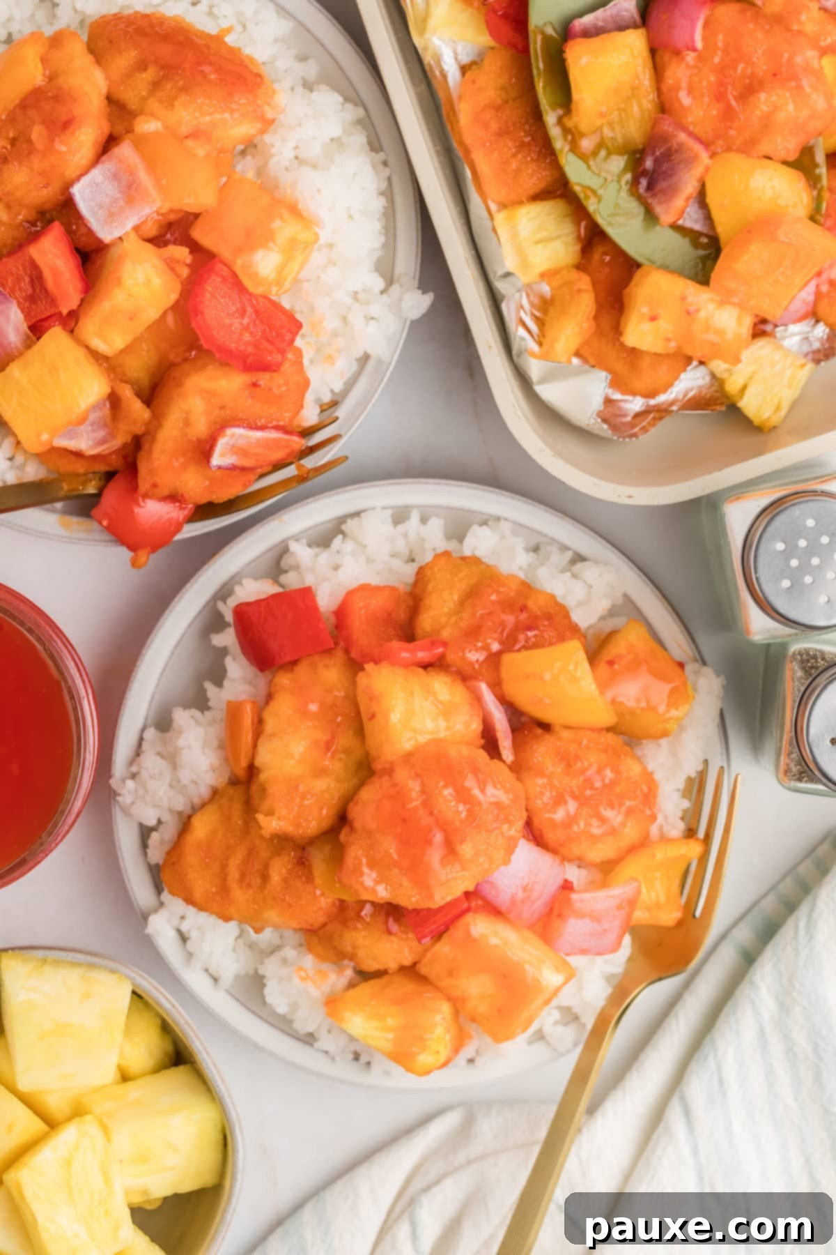 Bowl of cooked rice topped with sweet and sour chicken.